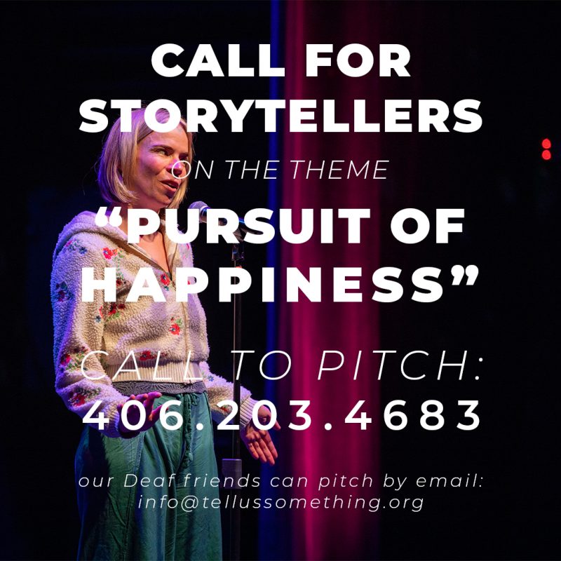 This image is a promotional graphic or flyer announcing a call for storytellers. It features a photograph of a person on stage overlaid with large, bold text.Visual Elements The Speaker: On the left side of the frame, a fair-skinned person with short blonde hair stands on a stage speaking into a microphone. They are wearing a textured, cream-colored zip-up hoodie with small floral embroidery and teal or green pants. They are captured mid-speech with an expressive facial countenance and an open gesture with their left hand. The Background: The stage background is dark, featuring a vertical strip of deep pink/red stage lighting behind the speaker, mimicking a curtain or spotlight effect. Overlaid Text The text is written in a clean, white, sans-serif font, using a mix of heavy bolding and light italics: CALL FOR STORYTELLERS (Large, bold caps) ON THE THEME (Smaller, light italic caps) “PURSUIT OF HAPPINESS” (Very large, bold caps) CALL TO PITCH: (Medium, light italic caps) 406.203.4683 (Large, bold phone number) our Deaf friends can pitch by email: info@tellussomething.org (Small, lowercase italic text at the bottom) photo by kmr studios